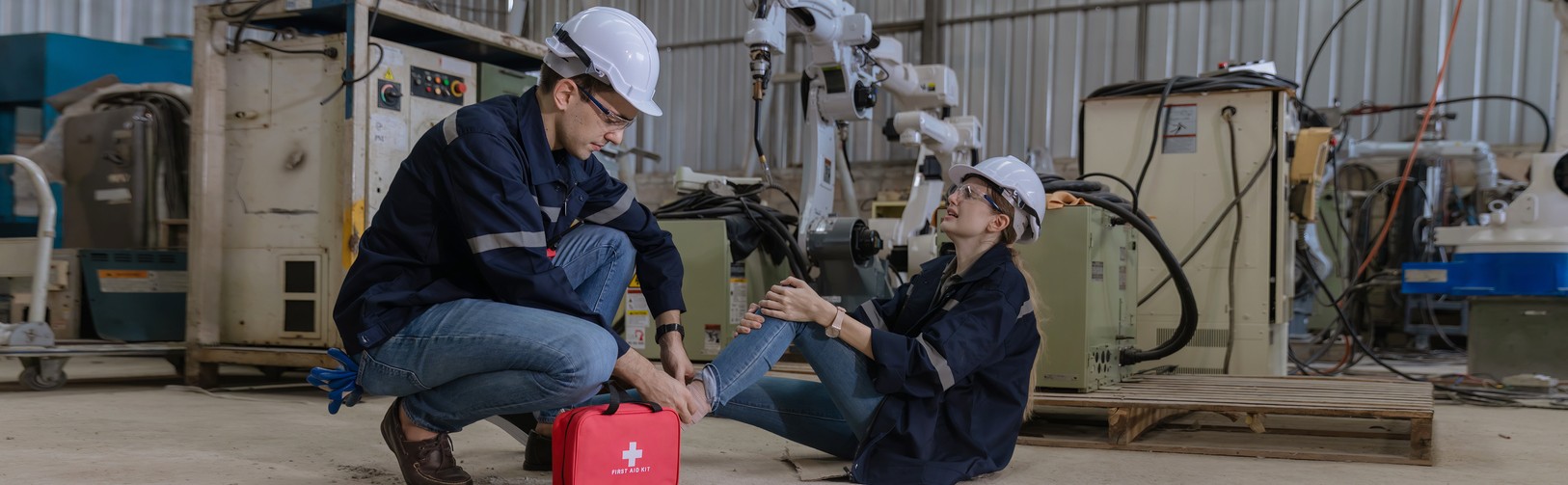 Injured worker with hard hart on the floor getting help from another worker.
